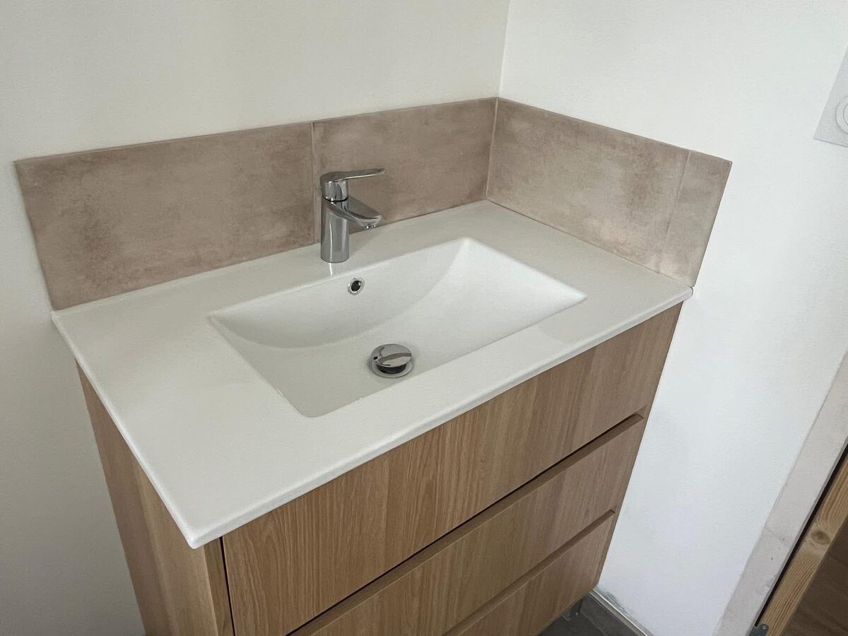 Bathroom vanity with white basin, oak drawer unit and beige tile splashback in a Brighton property