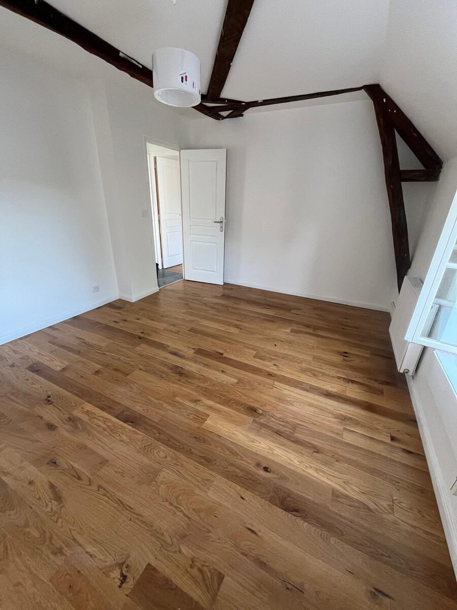 Completed solid oak floor in a Brighton attic bedroom with exposed dark-stained roof beams