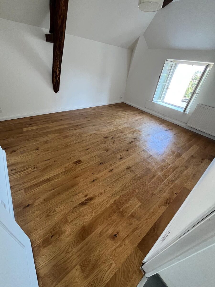 Completed solid oak floor in a Hove loft room with exposed ceiling beam and natural light